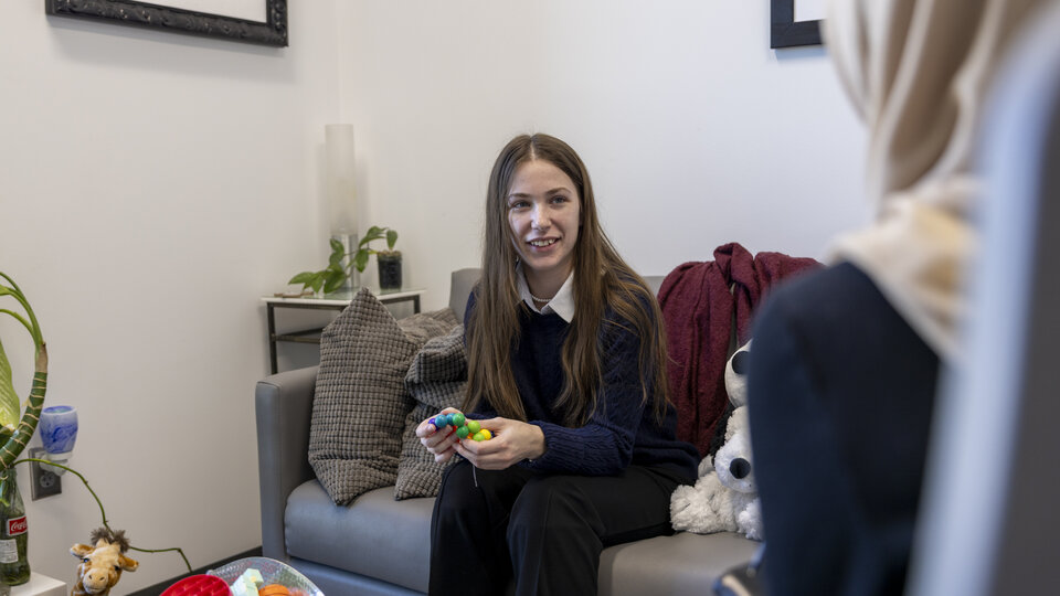 A white female student sits on a couch in an individual counseling appointment