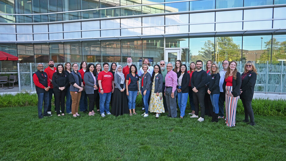 CAPS staff stand in front of the Health Center in two rows, all smiling and facing forward.