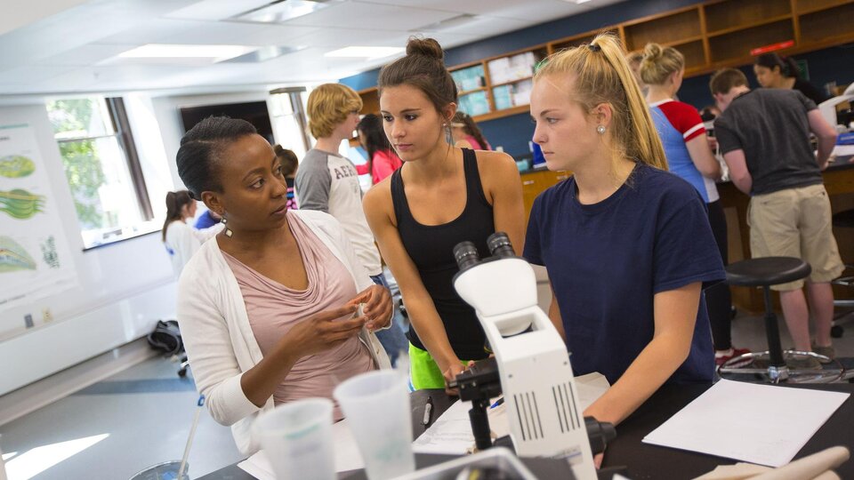 Students interact with an instructor in a lab on campus