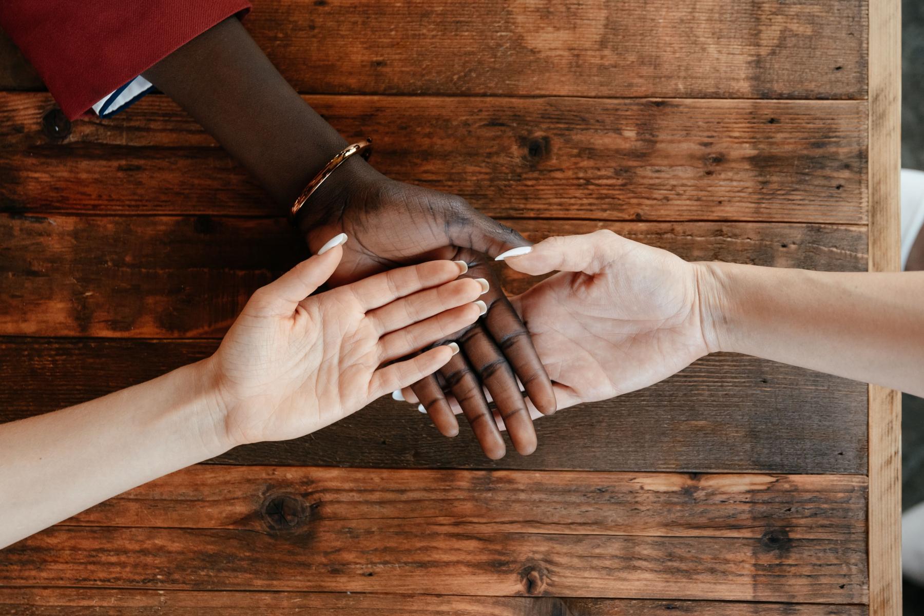 A diverse group of individuals with their hands one on top of the other