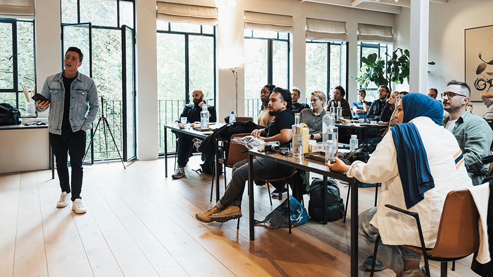 Group of individuals listen and watch a presentation.